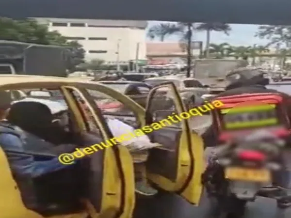"La embarran y ahora se bajan", motorizados a pasajeros de un taxi: les tiraron el carro encima y casi causa un accidente