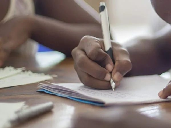 Niño escribiendo en libreta de colegio.
